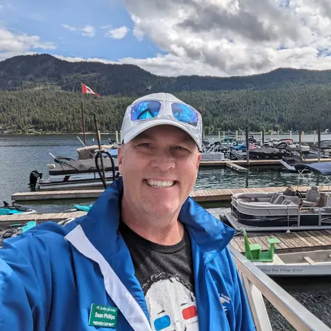 Sean Phillips smiling on a marina dock with pontoon boats behind him